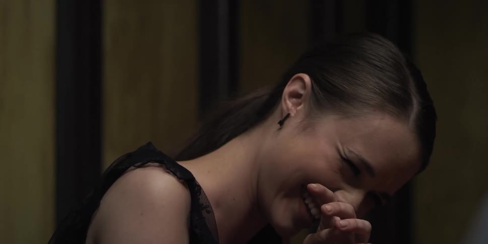 Young woman covers her face with a hand while laughing