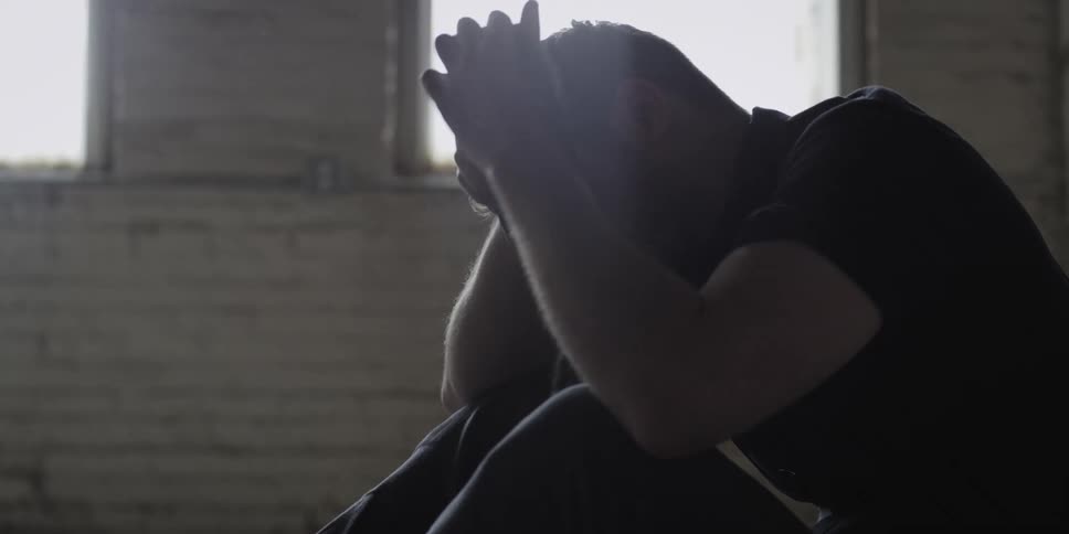 Young sad man crying sitting on the floor of a warehouse