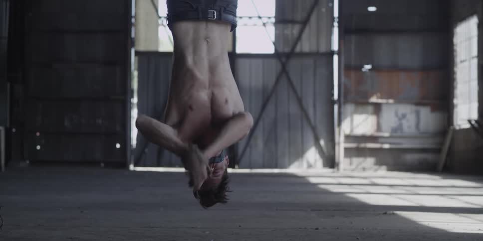 A man struggles as he is hung upside down and tied up