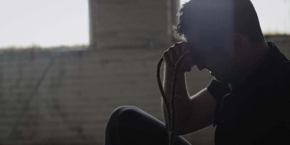 A man is sitting on the floor of a room and crying