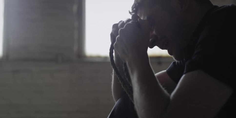 A man is sitting in an empty room and is sad