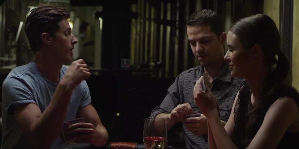 A group of people is sitting at a table playing a card game