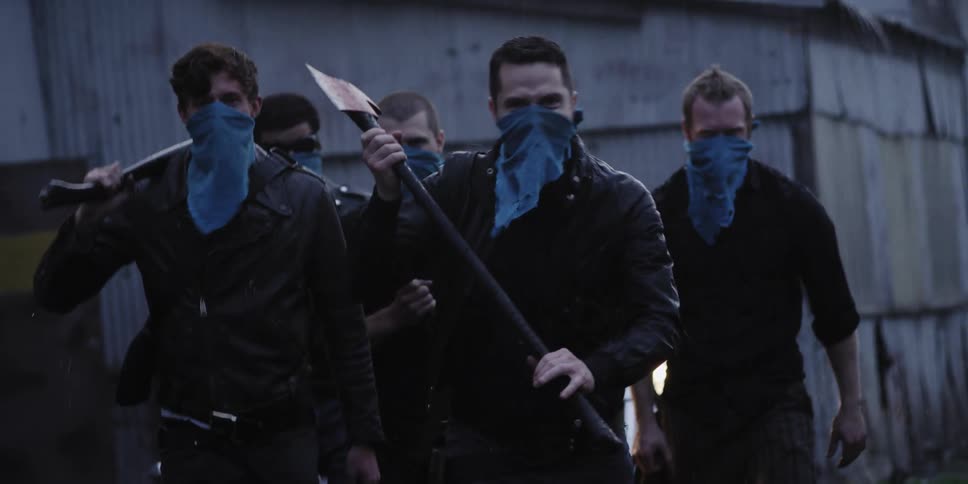 A group of men holding weapons start to run away from a building