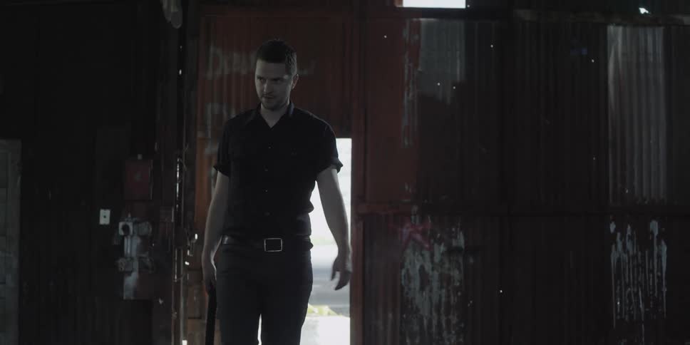 A man walks aggressively as he holds a weapon in his hand