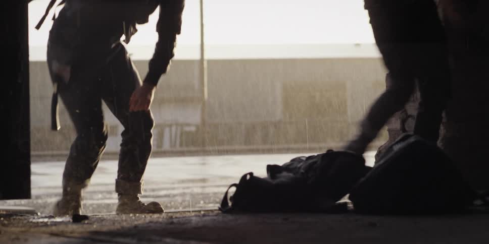 Two men throwing bags in a room with a building rain the sky and clouds in the background