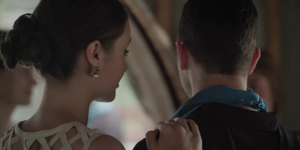 A woman holding a mans shoulder and kissing him on his cheek