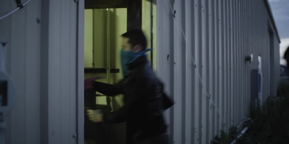 A man with a mask on uses an axes to break a door down and then him and four other men go in to the building