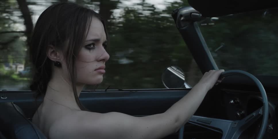 A woman frowns as she looks over while driving