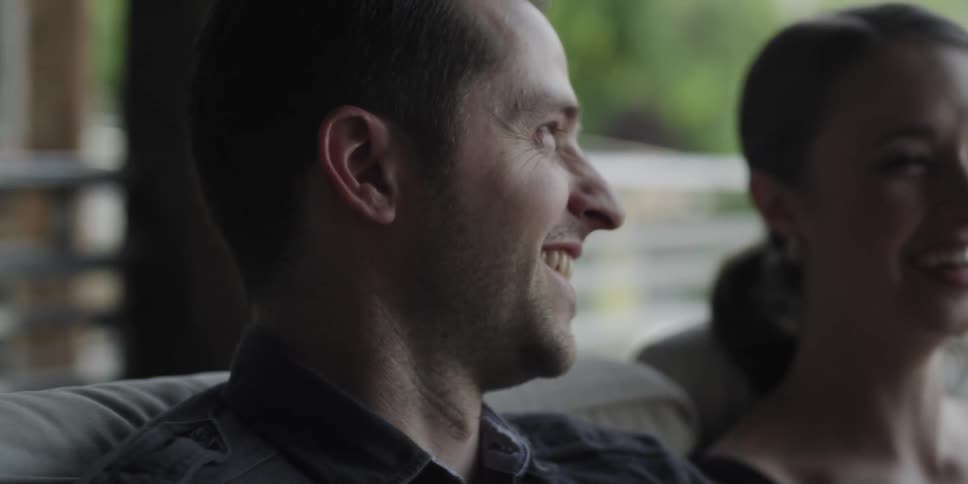 Young couple sitting on a couch at home laughing and smiling