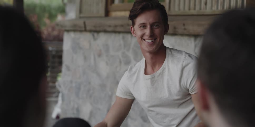 Man with white t shirt looks and smiles at man and woman