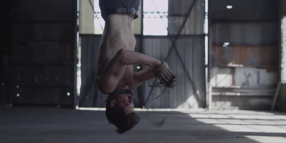 A man is hanging upside in a garage and is trying to break free
