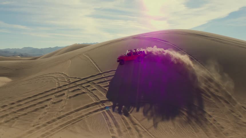 Red jeep vehicle drives on desert hill turning