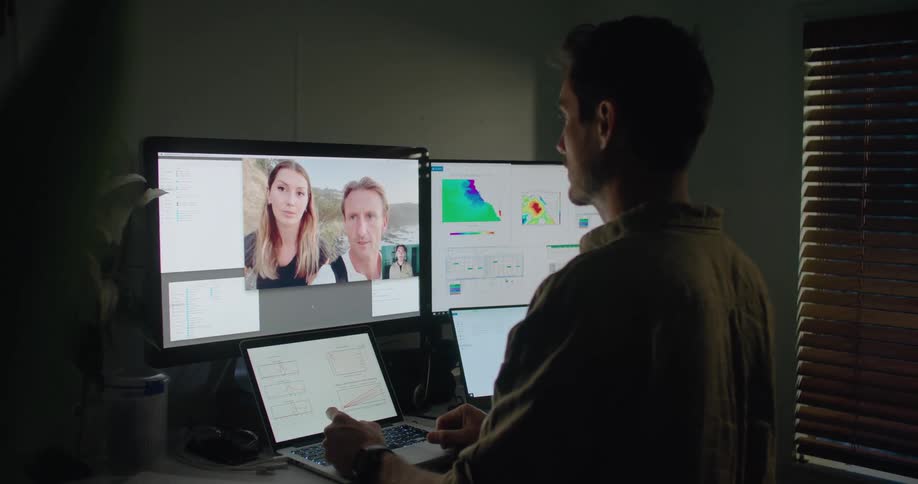 Man has discussion with two others on site near ocean via computer
