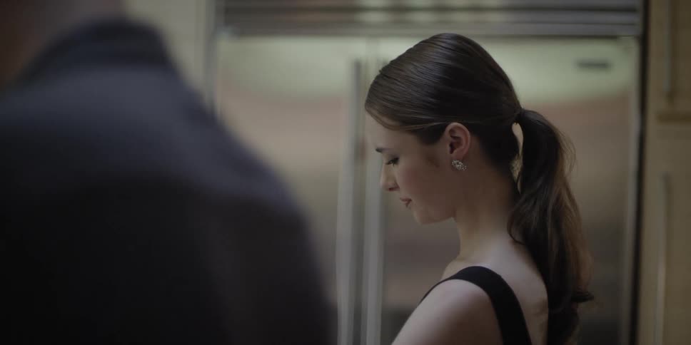 Woman stands in kitchen talking and smiling with man with metal finish refrigerator in background