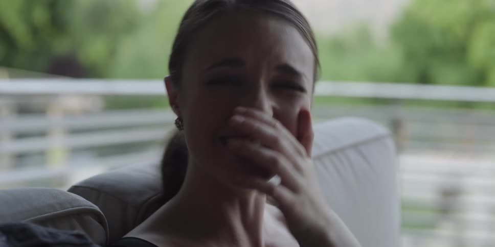 Woman covers her mouth while laughing before turning to look at friend