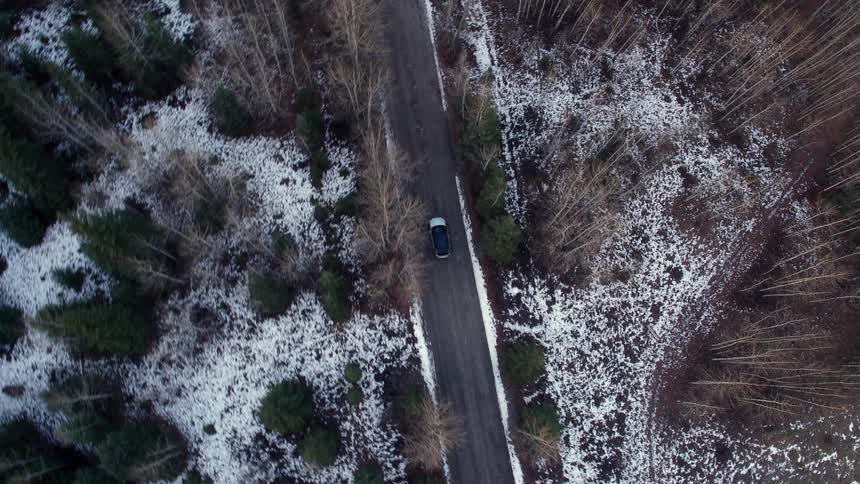 Car driving on a road through the forest at winter