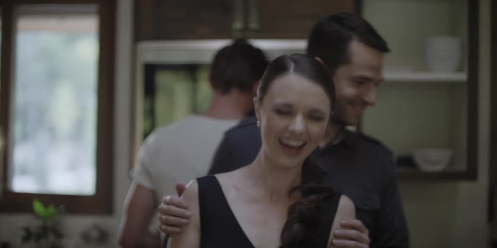 Two men and a woman in a room with a wall and window in the background