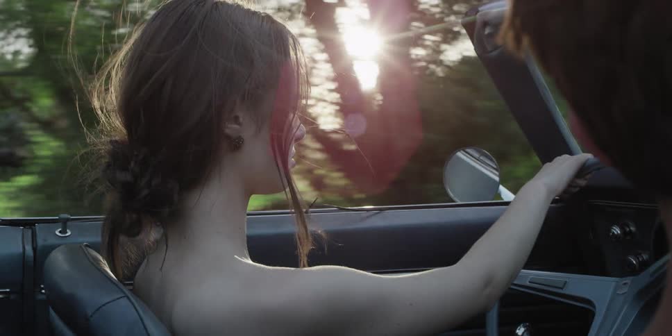 A woman looks ahead as she drives a convertible car