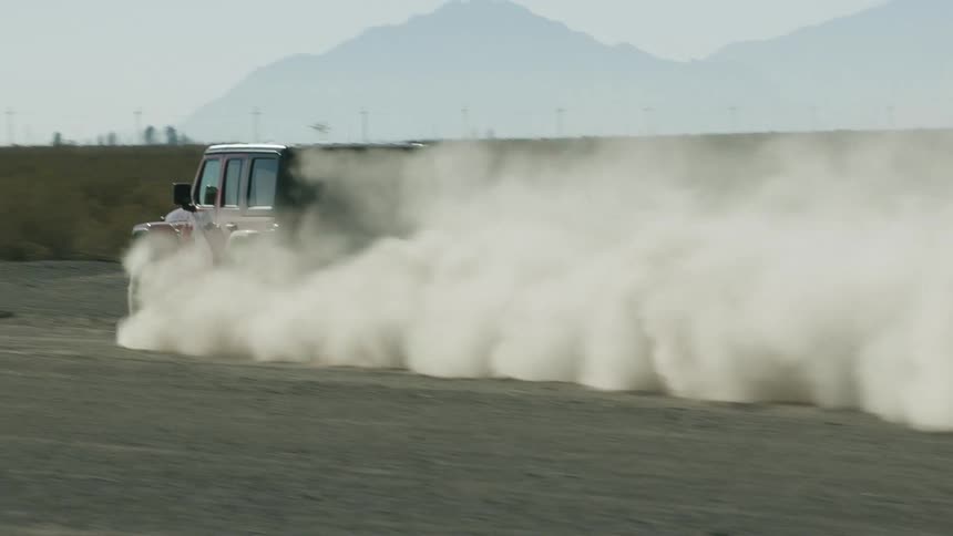 Car driving on a rural dirt road on the desert near the mountains