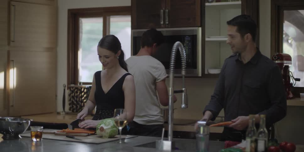 A man and woman talk while peeling and cutting carrots in a kitchen