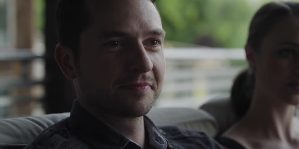 Close up of a young man sitting on a couch nodding while listening
