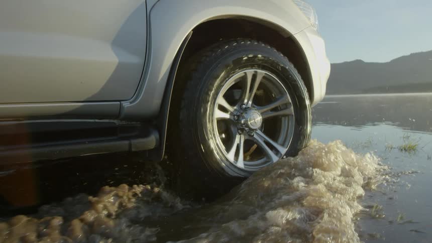 A car drives through water on a flooded section of land