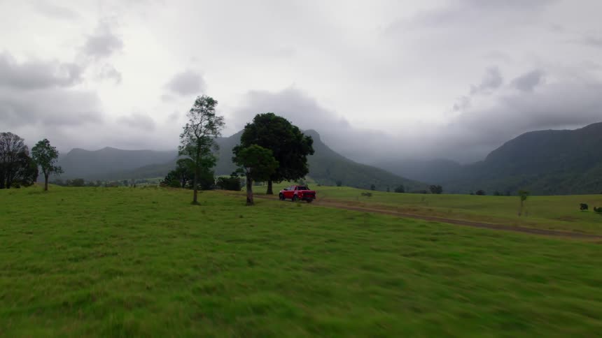 A vehicle is driving along a dirt road in the mountains