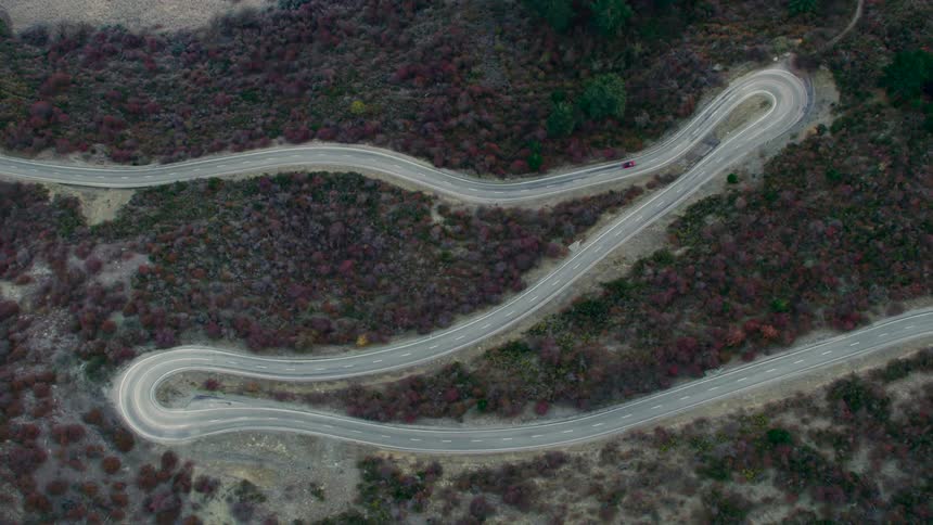 Aerial view of a red car traveling on a winding road