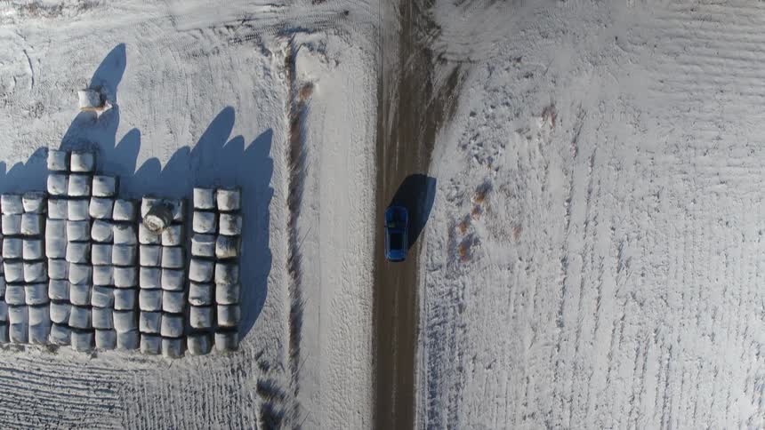 A car drives past the snow covered fields