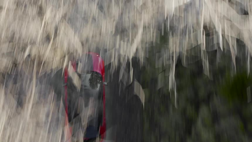 A red vehicle speeds down a narrow rural road