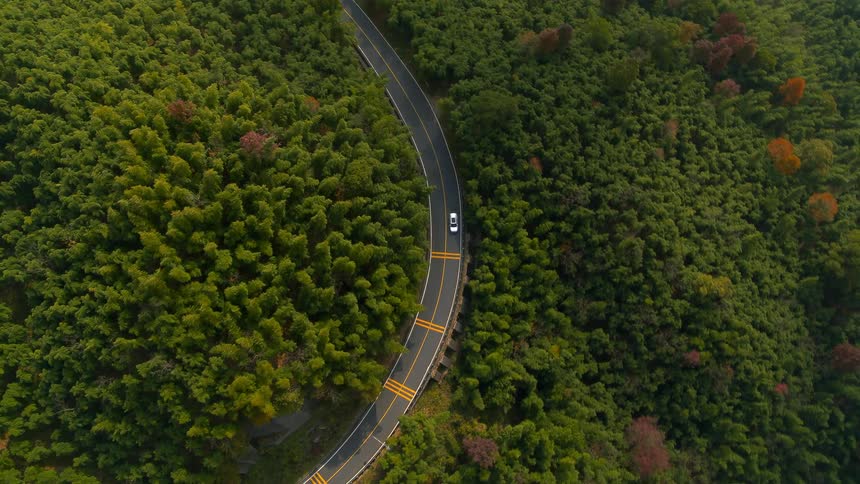 An aerial view of a car driving down a windy road