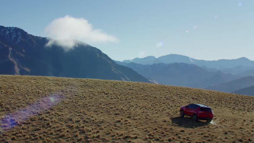A car is driving near the mountains at midday