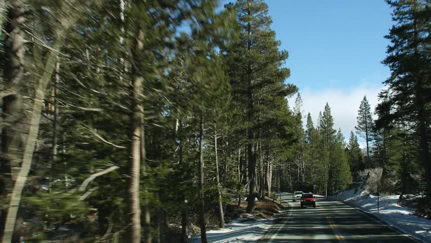 Cars driving down a road with snow on the side