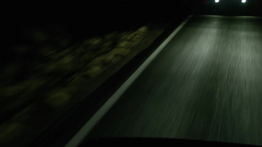 A vehicle with headlights driving on a road