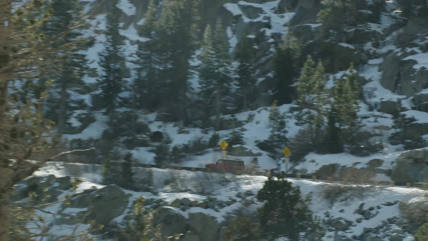Aerial view of a red vehicle driving on a road in the snow covered mountain