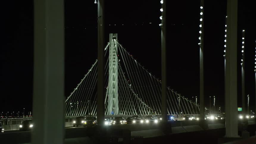 Vehicles driving on a bridge with the sky and signs in the background