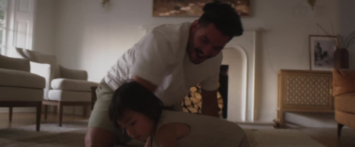 A father is on the living room floor playing around with his child