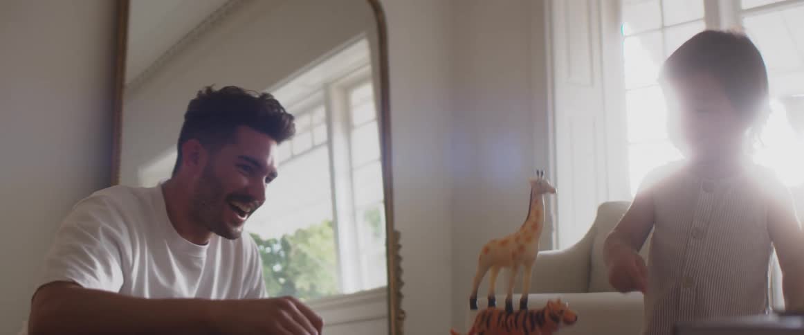 A man and a child high five one another near a table with toy animals stacked on top of one another