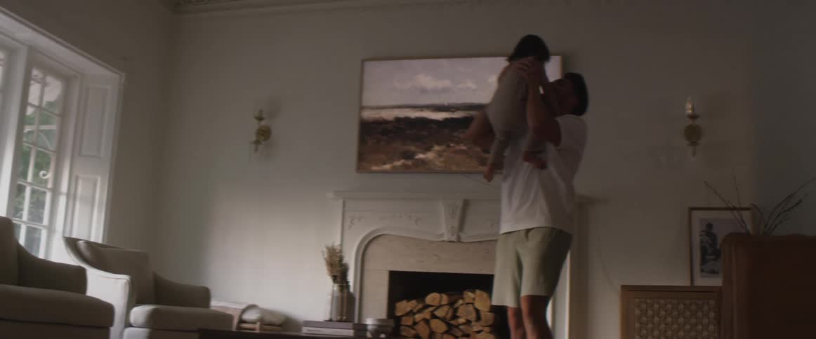 A man playfully lifts a small child into the air before lowering them back down to the floor