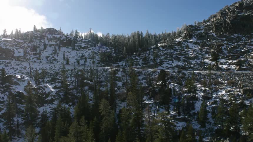 An automobile travels on a mountain road on a winter day