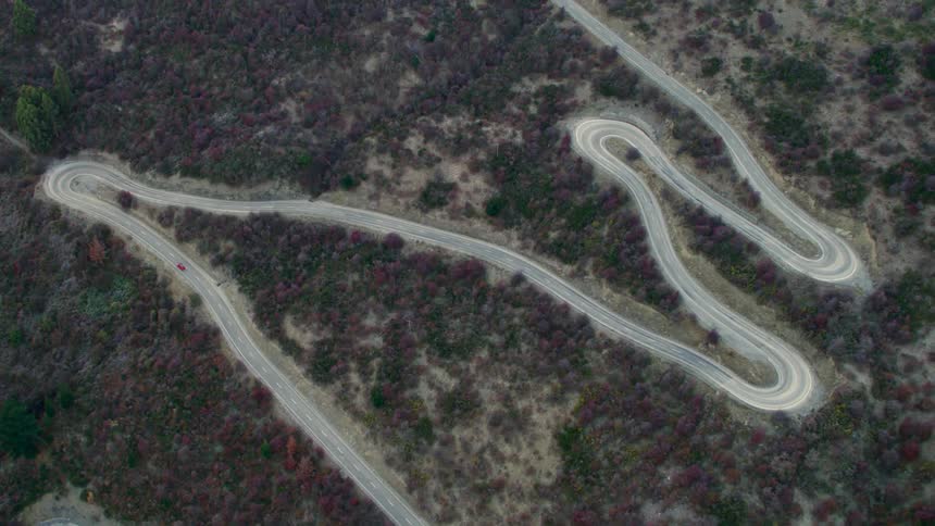 Aerial view of a red car traveling on a winding road