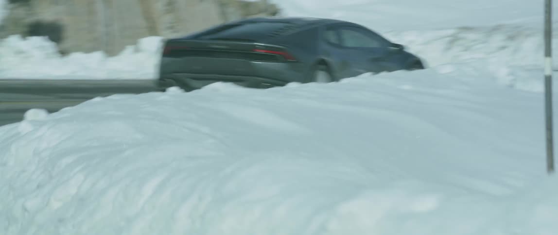 A car turns around a road surrounded by snow