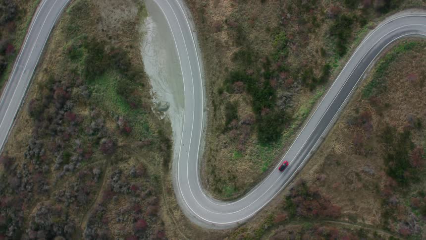 A birds eye view of a car traveling on a winding mountain road during the day