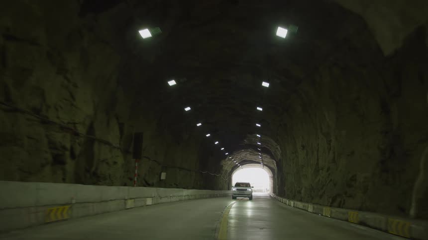 A vehicle is traveling through a mountain tunnel during the daytime