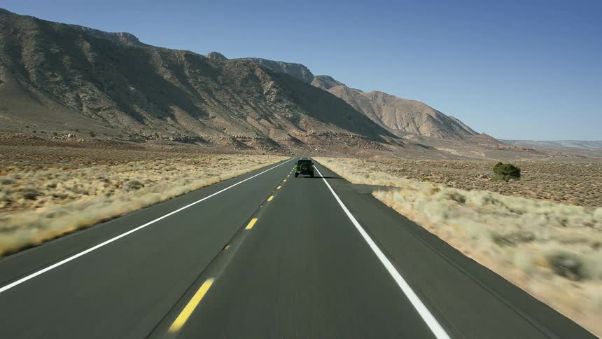 A lone vehicle drives down the highway