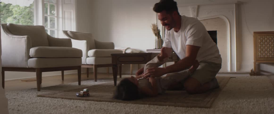 Father playing with child on the floor of the living room at home