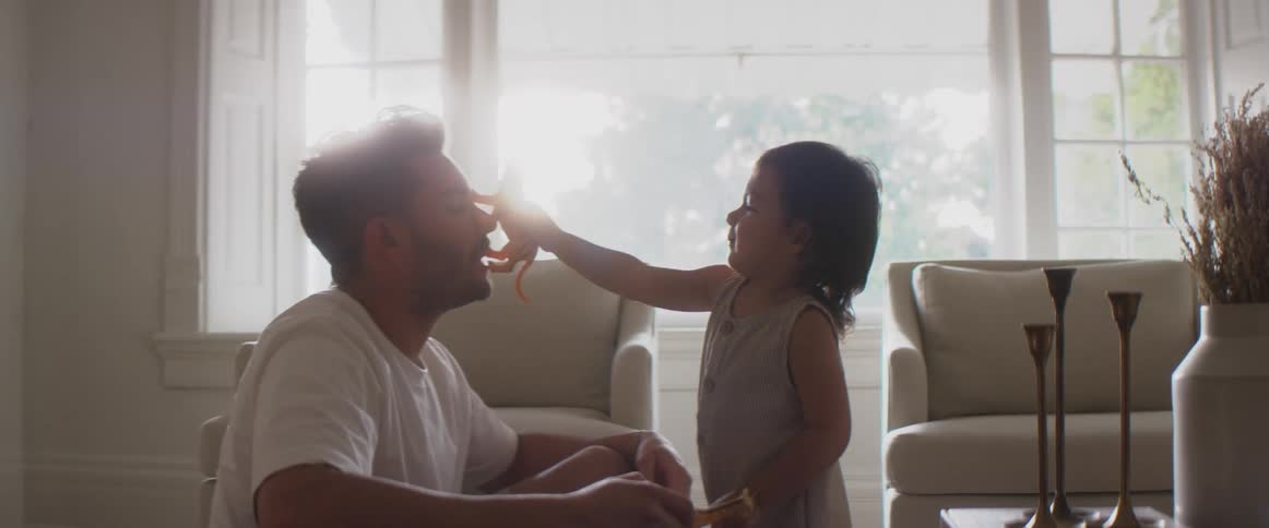 A child walks a plastic animal on fathers face before he grabs and hugs him