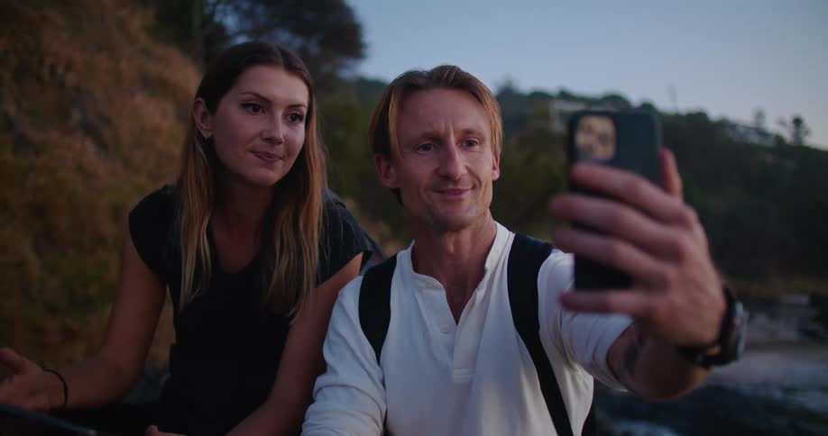 A man is holding a phone so he and a woman can talk with someone