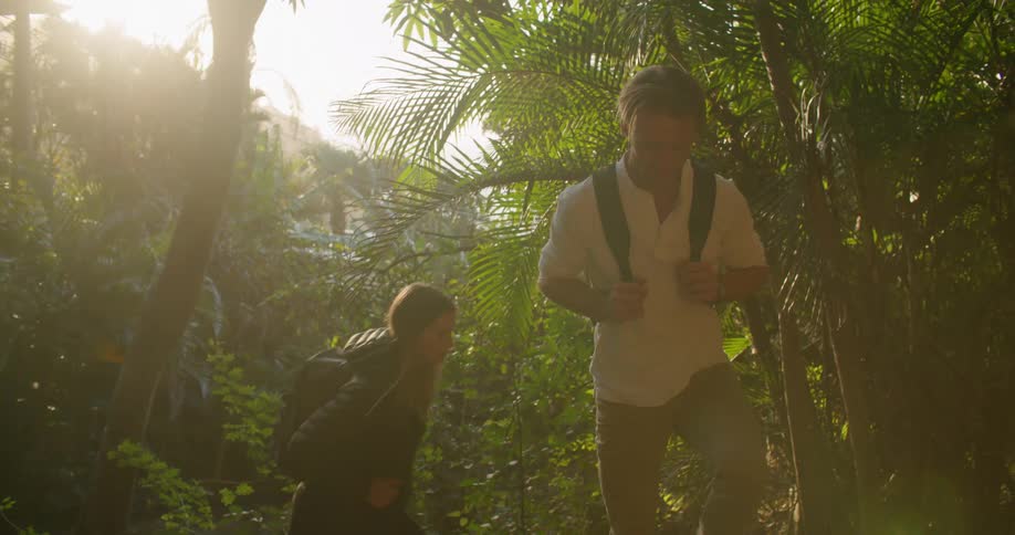 Man and woman are hiking through a forest together at dusk