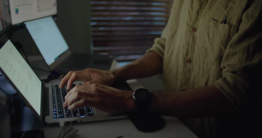 A man is typing on a laptop at night